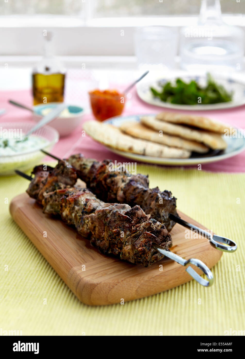 Gegrillte griechische Souvlaki Chicken Kebabs mit Tzatziki Sauce an Bord vor dem Fenster mit Pita Brot Stockfoto