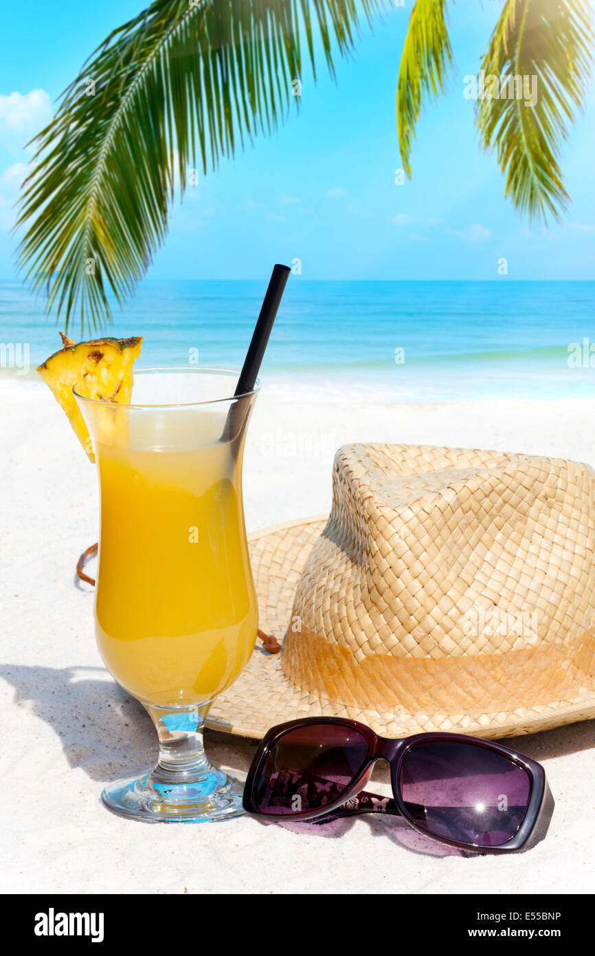 Tropischen Cocktail in den Sand am Strand mit dem Meer im Hintergrund ...