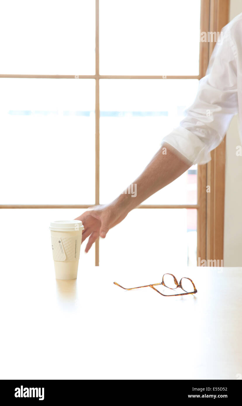 Mann erreicht für Kaffee bei der Arbeit Stockfoto