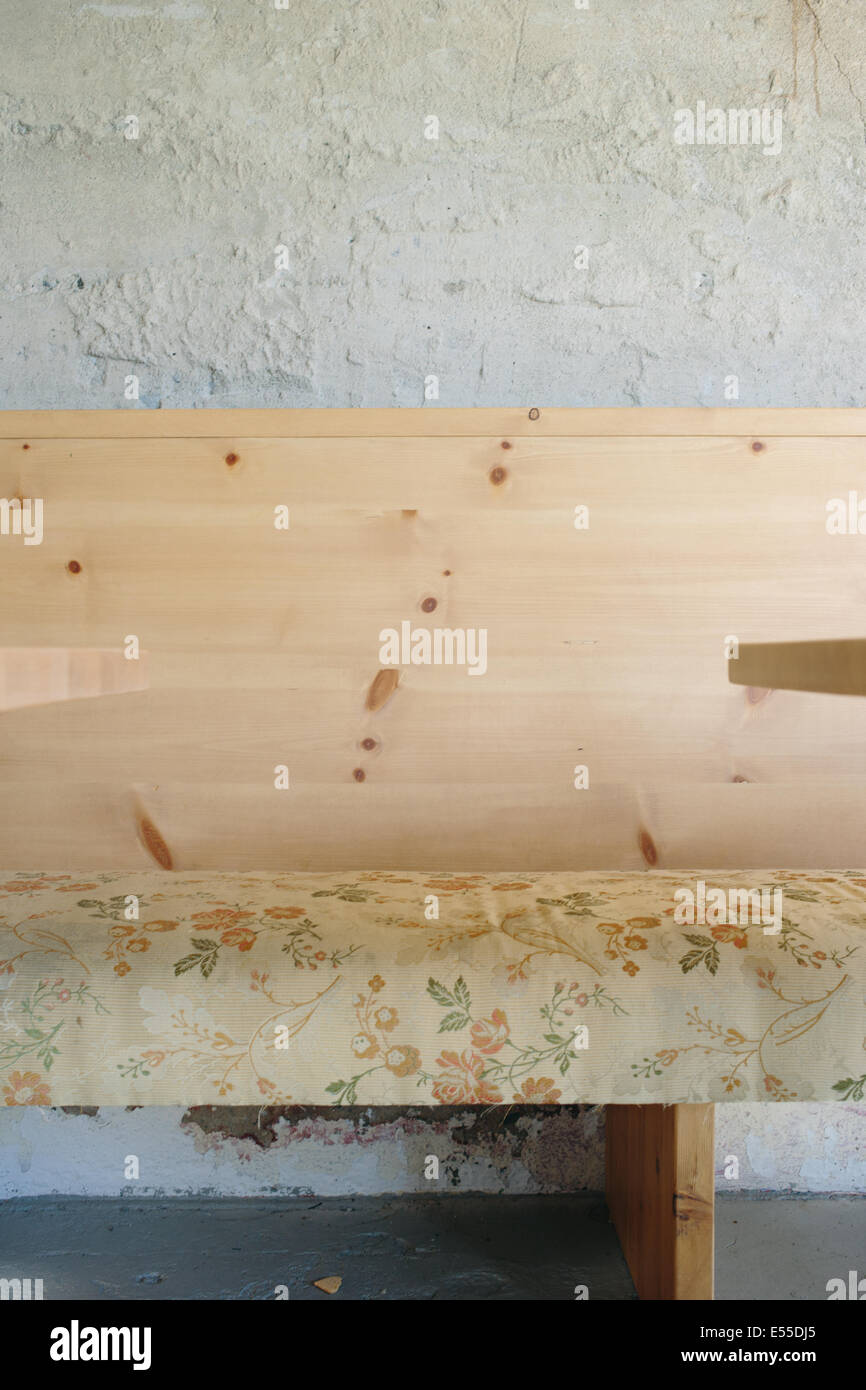 Minimalen Schuss von floralen Polsterbank mit Holz Rücken gegen die Betonwand. Stockfoto