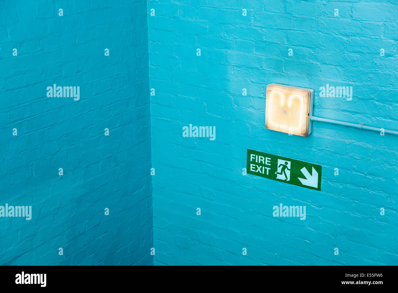 Blaue Wand-Ecke mit Notausgangsschild und Lampe Stockfoto