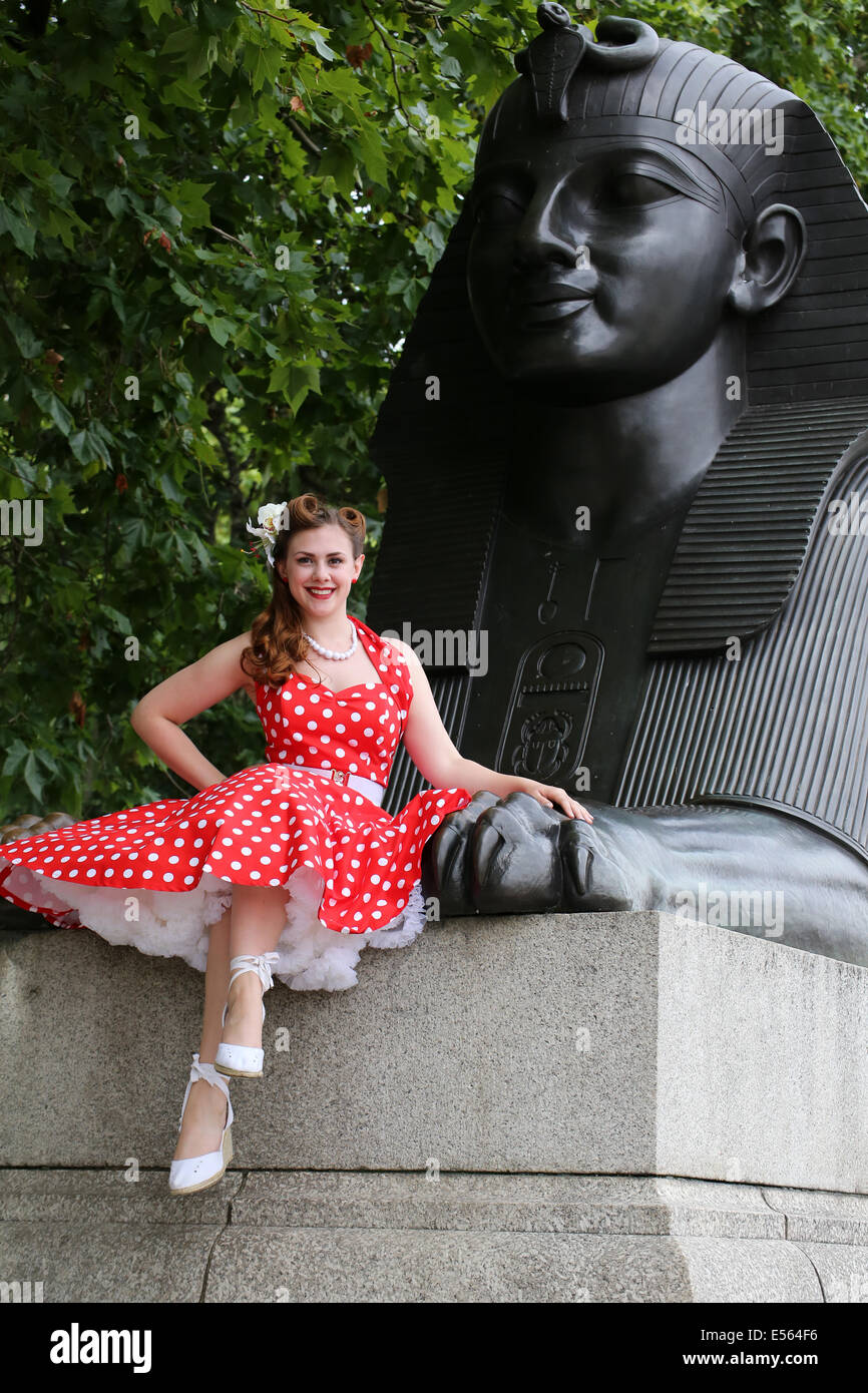 Frau in helles rot gepunkteten Kleid sitzt auf der Sphinx auf London Damm Stockfoto