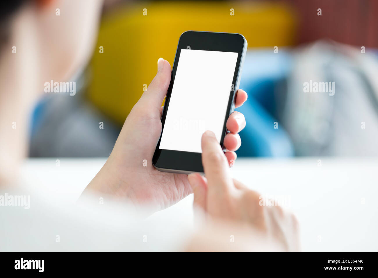 Frau mit modernen Mobiltelefon in Händen berühren auf einen leeren Bildschirm. Verschwommene Büroeinrichtung auf einem Hintergrund. Stockfoto