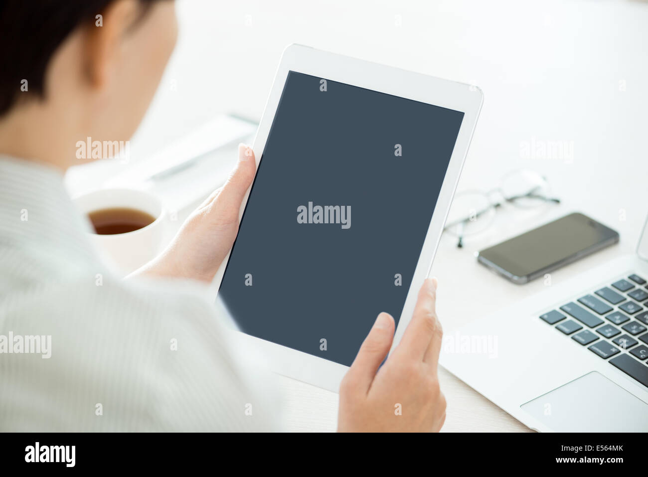 Geschäftsperson halten moderne digital-Tablette und blicken auf einen leeren Bildschirm. Stilvolle moderne Büro-Arbeitsplatz auf einem Hintergrund. Stockfoto