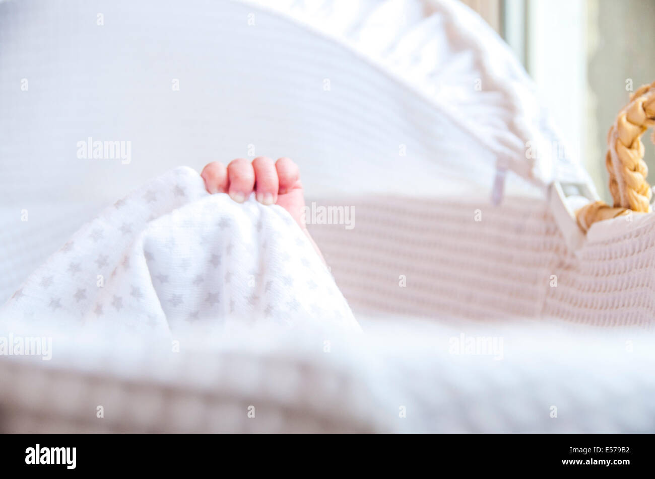 Neugeborenes Baby erstreckt sich in einem hellen und luftigen Kindergarten Körbchen Stockfoto