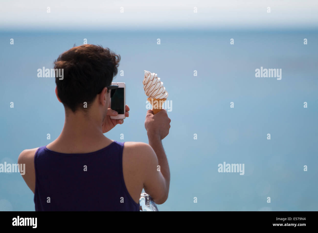 Aberystwyth, Wales, UK. 22. Juli 2014. Ein junger Mann nimmt ein Bild von seinem Eis am Meer, als wieder einmal die Temperaturen in Aberystwyth steigen. Bildnachweis: Jon Freeman/Alamy Live-Nachrichten Stockfoto