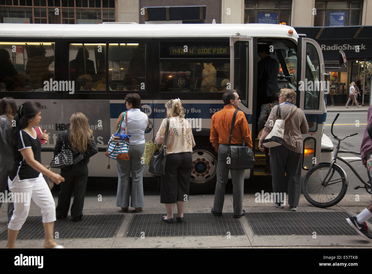 Menschen warten auf ein crosstown Bus entlang der 42nd Street in Manhattan, NYC. Stockfoto