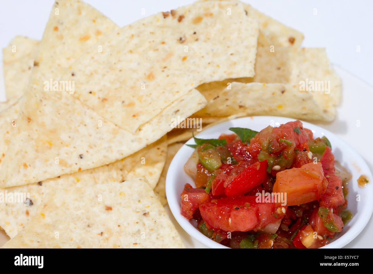 Tortilla-Chips und Salsa in eine Schüssel geben. Hintergrund ist weiß. Stockfoto