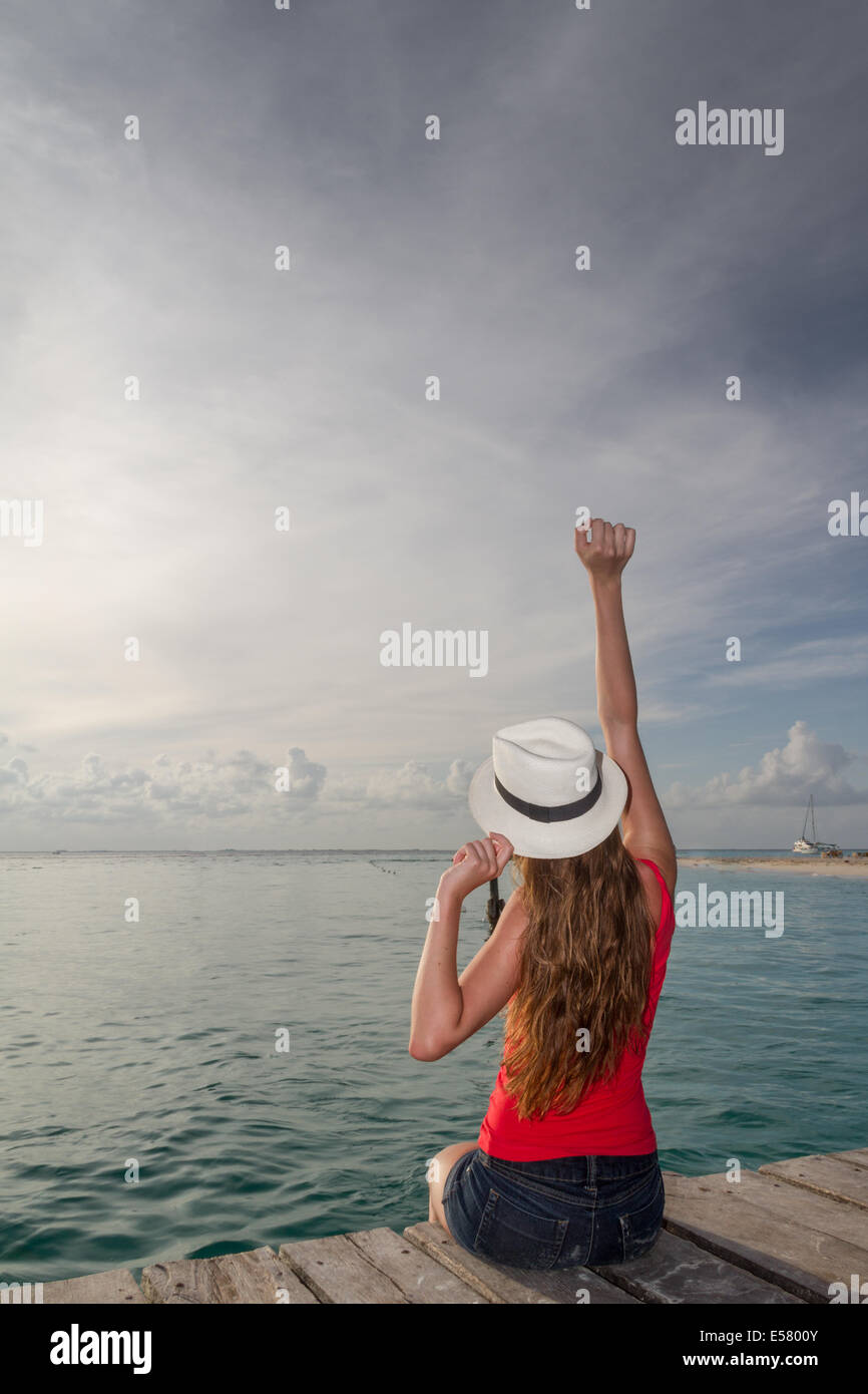Junge Frau Gruß den Sonnenuntergang an der pier Stockfoto