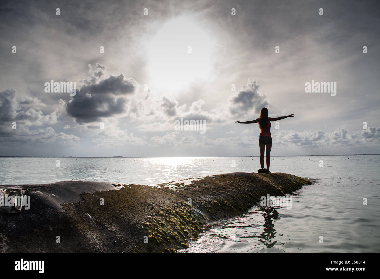 Junge Frau am Rande des Meeres streckt in den Himmel, genießen Sie einen unglaublichen Sonnenuntergang Stockfoto