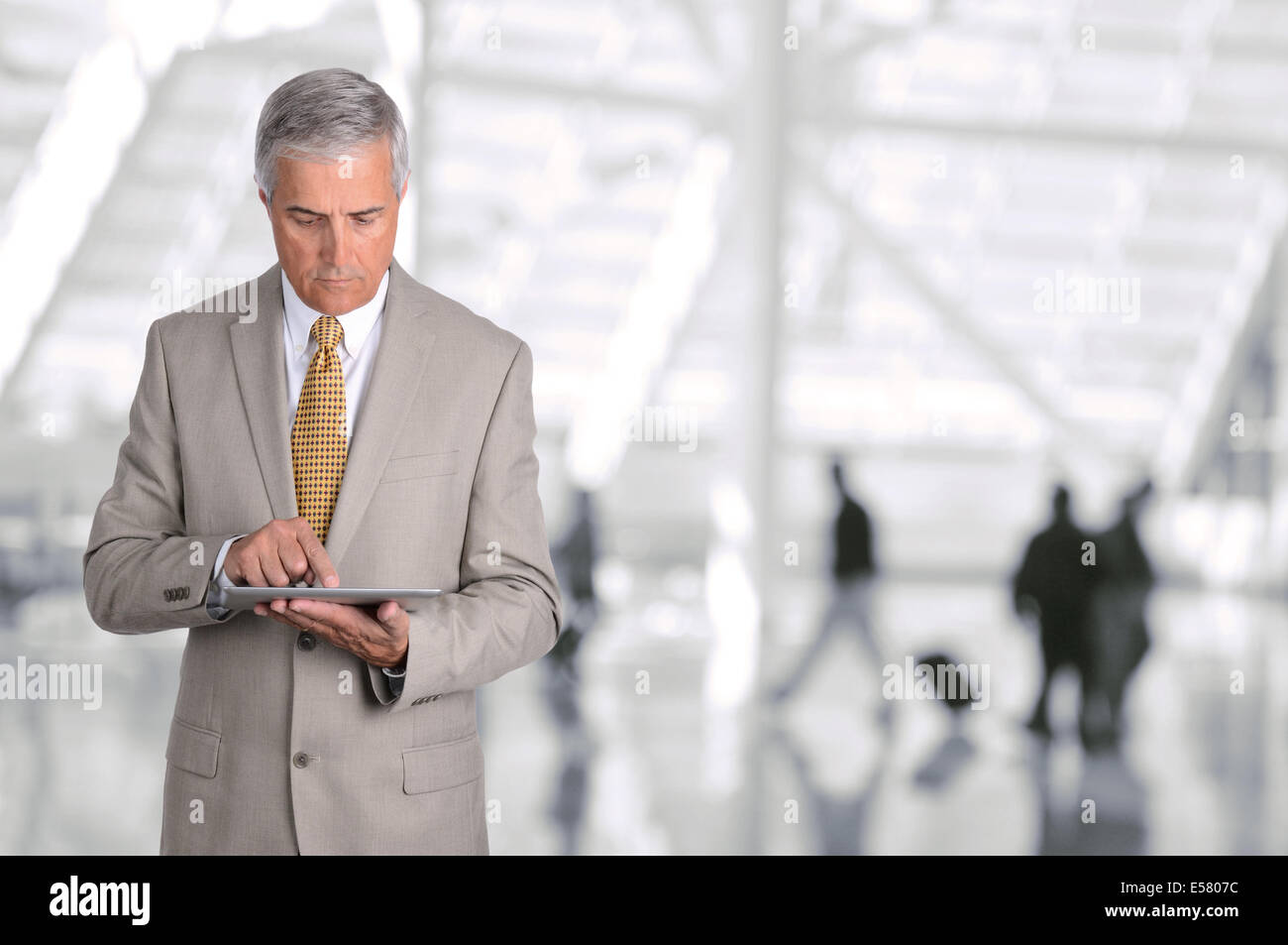 Nahaufnahme eines ausgereiften Geschäftsmann mit seinem Tablettcomputer in einer Flughafen-Halle. Der Mann ist am Gerät mit unscharfen suchen Stockfoto