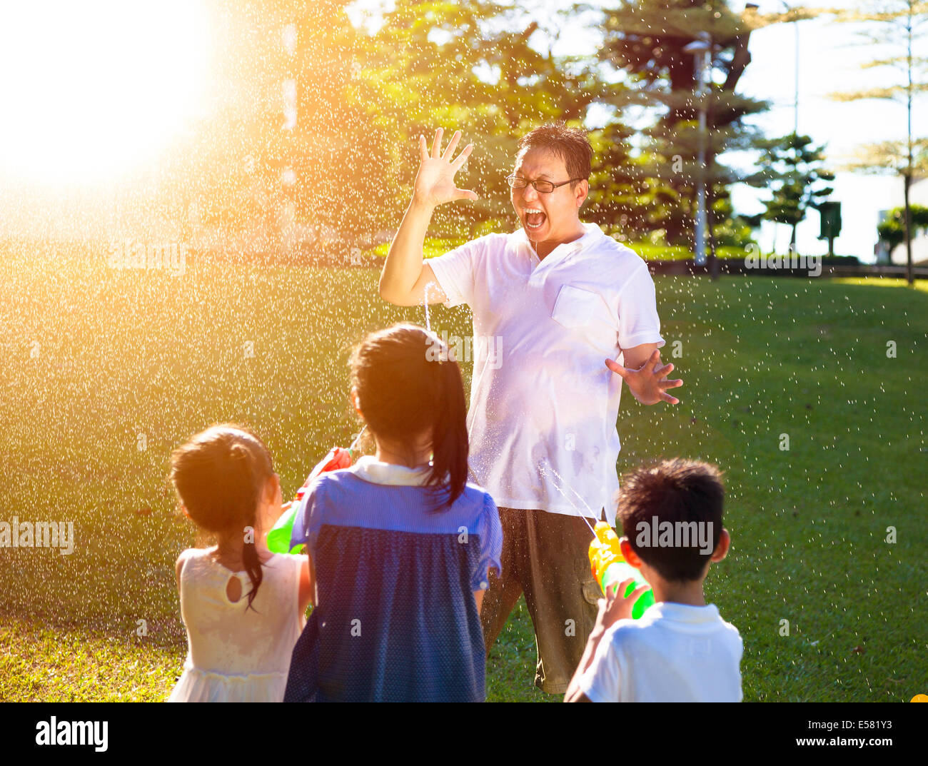 Kinder sprühen Wasser zusammen mit Wasserpistolen Vater Stockfoto