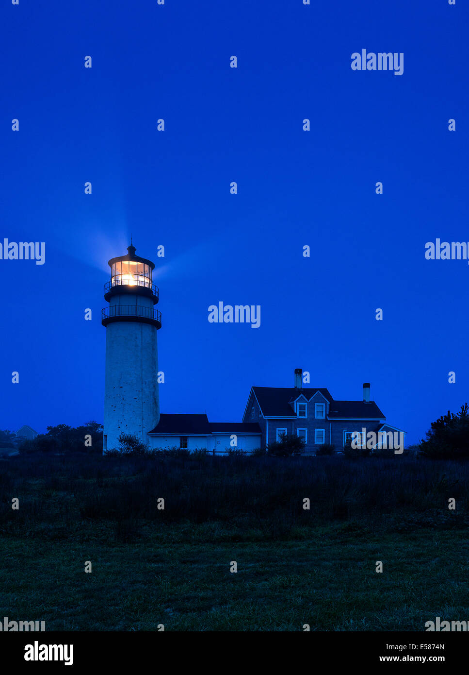 Leuchtturm wirft Licht in dunkle blaue Nacht, Stockfoto