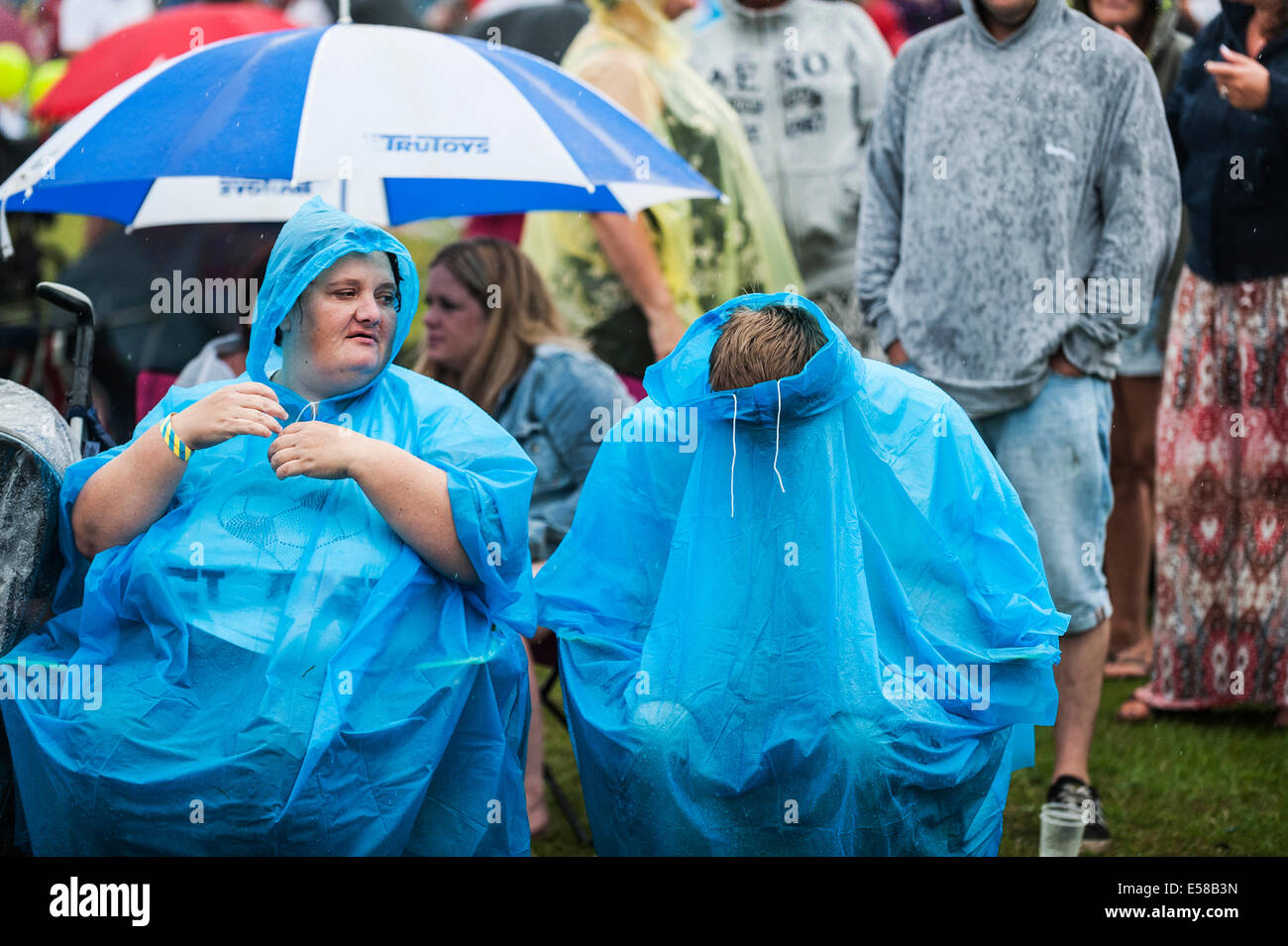 FestivalbesucherInnen schützt vor schlechtem Wetter auf dem Festival in Brentwood. Stockfoto