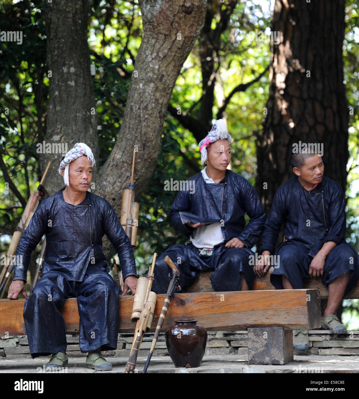 Congjiang, Chinas Provinz Guizhou. 23. Juli 2014. Männer der ethnischen Gruppe der Miao ruhen im Baum Schatten am Biasha, einem Miao-Ethik-Dorf in Congjiang County, autonome Präfektur von Qiandongnan der Miao-Dong, Südwesten Chinas Provinz Guizhou, 23. Juli 2014. Die lokalen Miao Leute hier halten Sie sich an ihren traditionellen Kostümen bis Tausende von Jahren zurückreicht. Wenn Waffen in China streng reglementiert sind, dürfen Männer in Biasha zu tragen und verwenden Sie Waffen, ihre Tradition zu schützen. © Xinhua/Alamy Live-Nachrichten Stockfoto