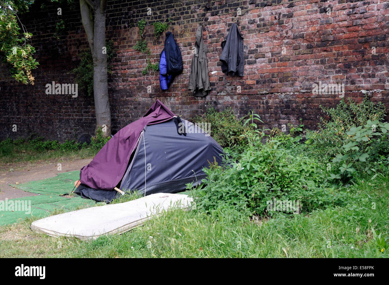 Obdachlose Personen Zelt am Leinpfad von Regent es Cannal mit Mäntel aufhängen an der Wand hinter London Borough of Islington England UK Stockfoto