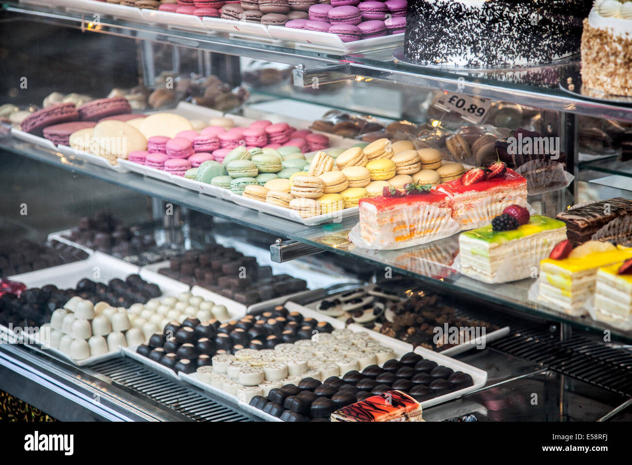 Eine Konditorei-Schaufenster mit einer Auswahl an Kuchen, Pralinen und Macarons in Kentish Town, London Stockfoto