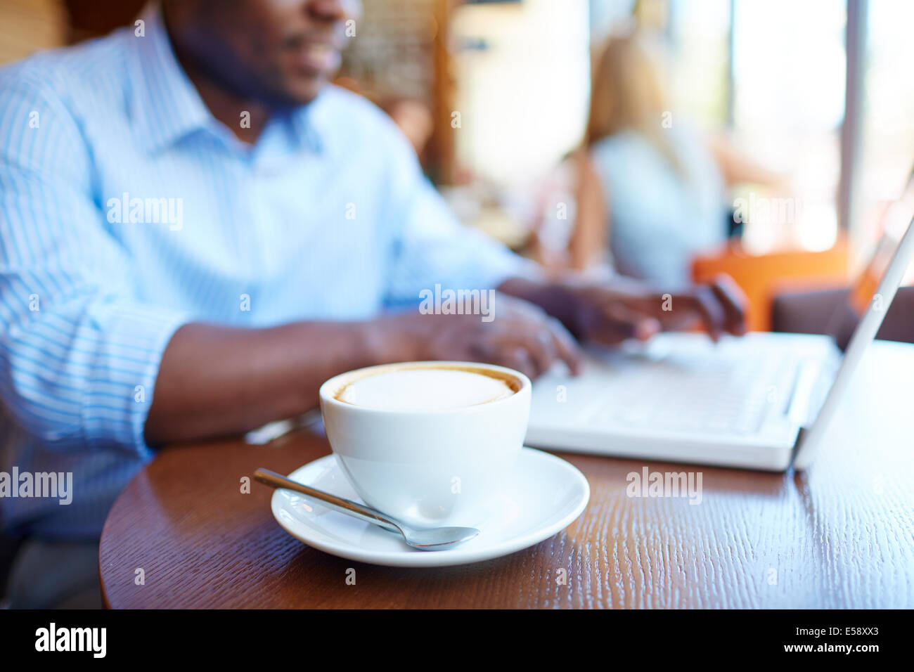 Bild der Tasse Latte auf Grund des Menschen tippen auf Laptop im café Stockfoto