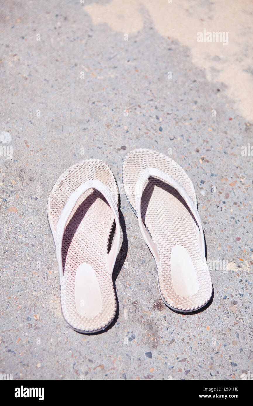 Nahaufnahme von paar alte und gebrauchte weiße Kautschuk Sandalen auf Betonoberfläche an heißen, sonnigen Sommertag Stockfoto