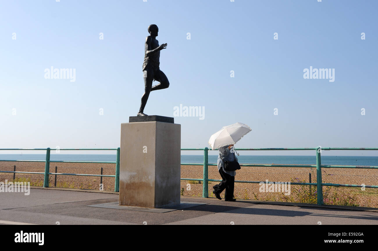 Brighton, Sussex, UK. 24. Juli 2014. Aufenthalt im Schatten eine Dame mit einem Regenschirm vorbei an Steve Ovett Statue auf Brighton Seafront in der frühen Wärme geht Temperaturen eingestellt sind, steigen in das heiße Wetter in ganz Großbritannien heute wieder Kredit: Simon Dack/Alamy Live News Stockfoto