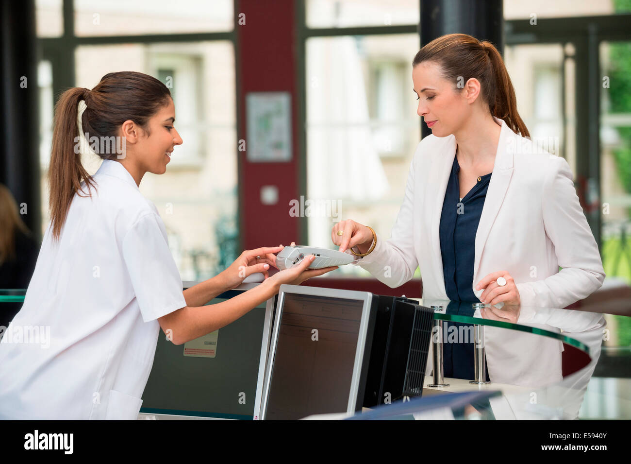 Ärztin, die die Zahlung mit Kreditkarte an Krankenhaus-Rezeption Stockfoto