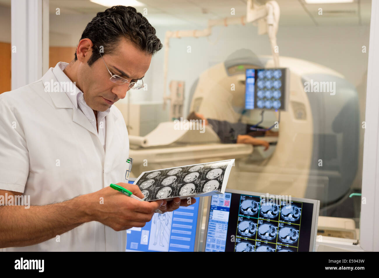 Männlichen Arzt untersuchen MRI Scan-Bericht in medizinischen Untersuchungsraum Stockfoto