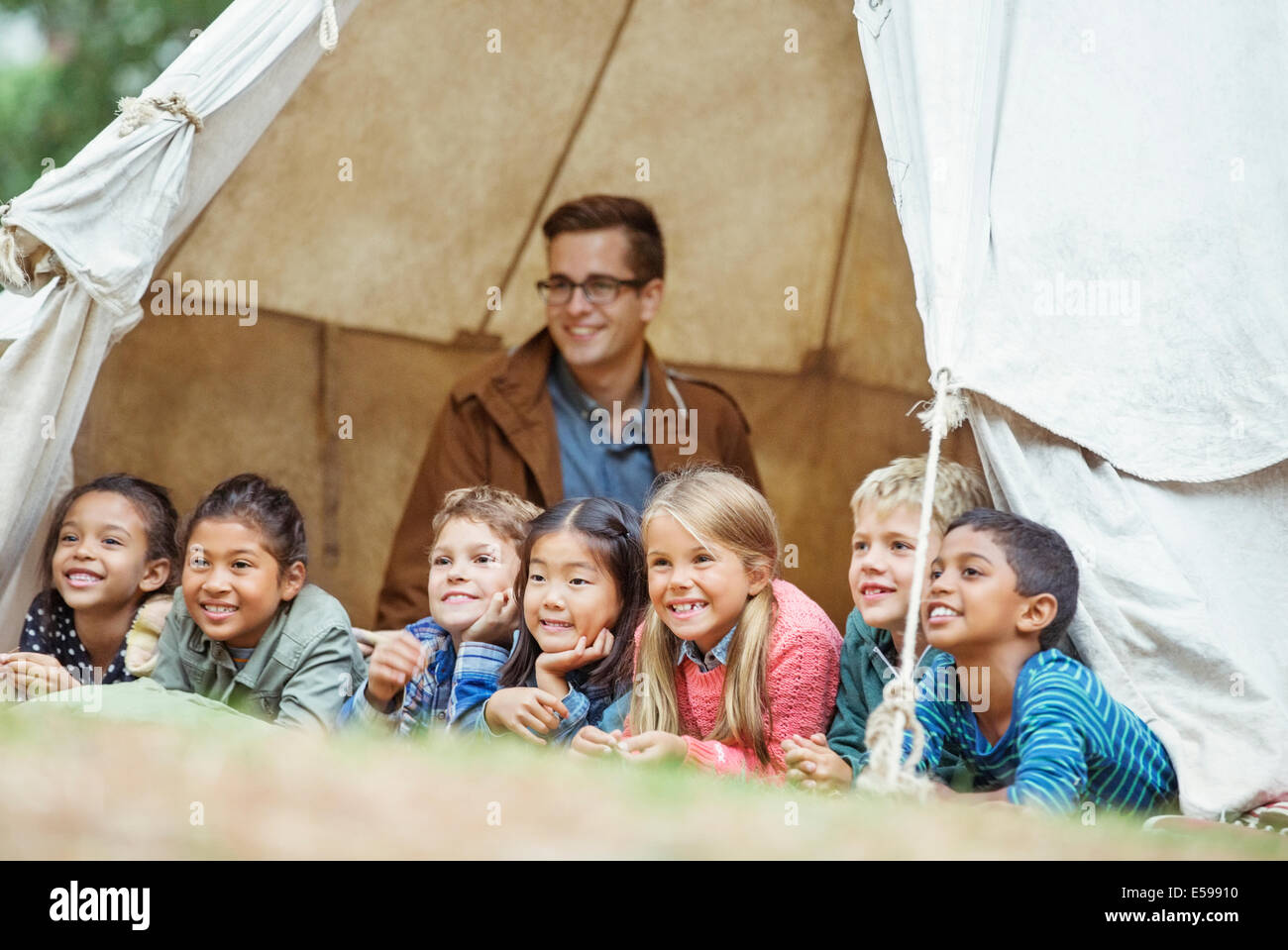 Schüler und Lehrer, die lächelnd im Zelt am Campingplatz Stockfoto