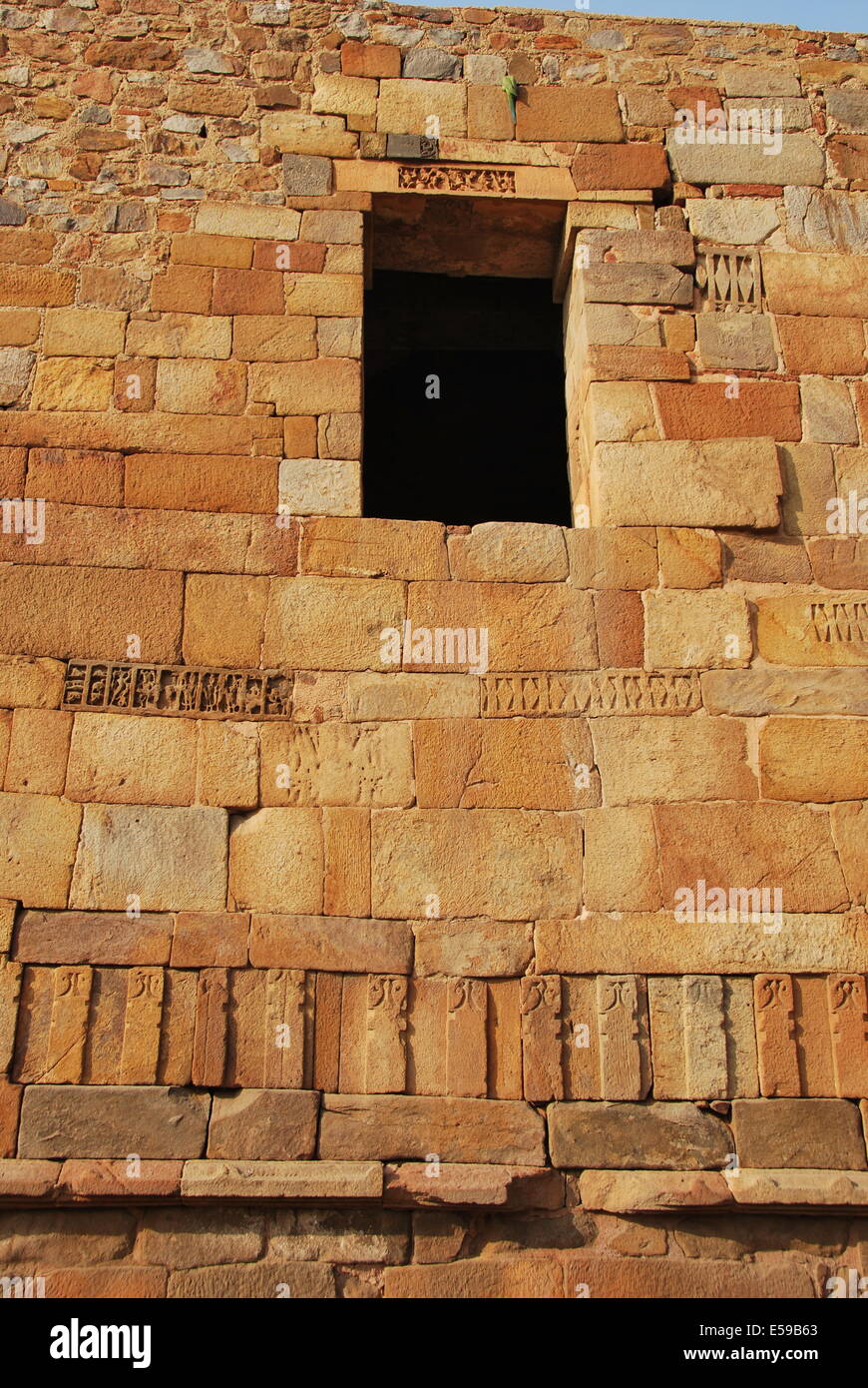 Indien. Delhi. Qutb Minar Komplex. Moschee. Natürlichen Sandsteinwand. Schnitzereien aus Sandstein. Sittich thront auf Stein oben öffnen Stockfoto