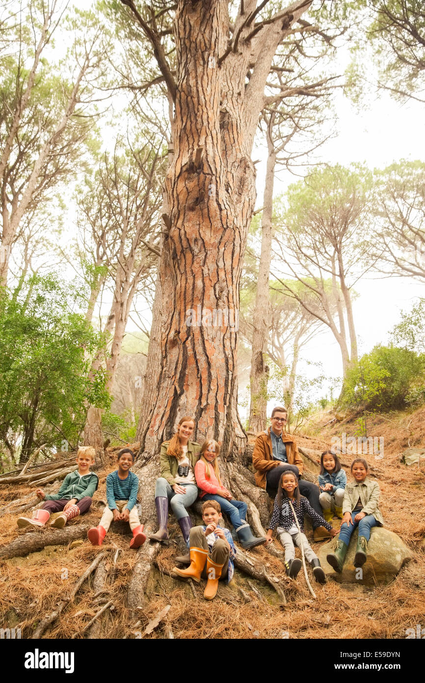 Schüler und Lehrer sitzen auf Baum im Wald Stockfoto