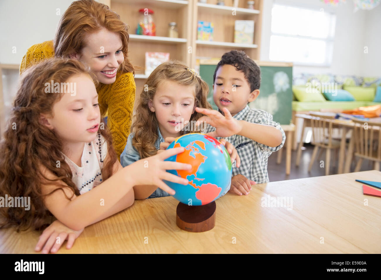 Schüler und Lehrer Prüfung Globus im Klassenzimmer Stockfoto