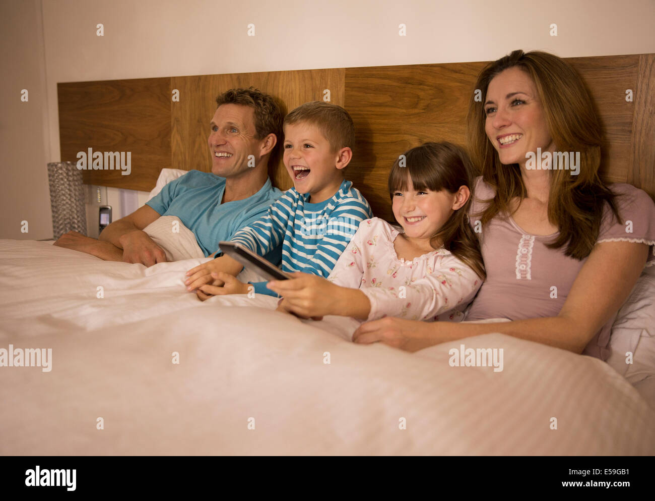 Familie vor dem Fernseher im Bett Stockfoto