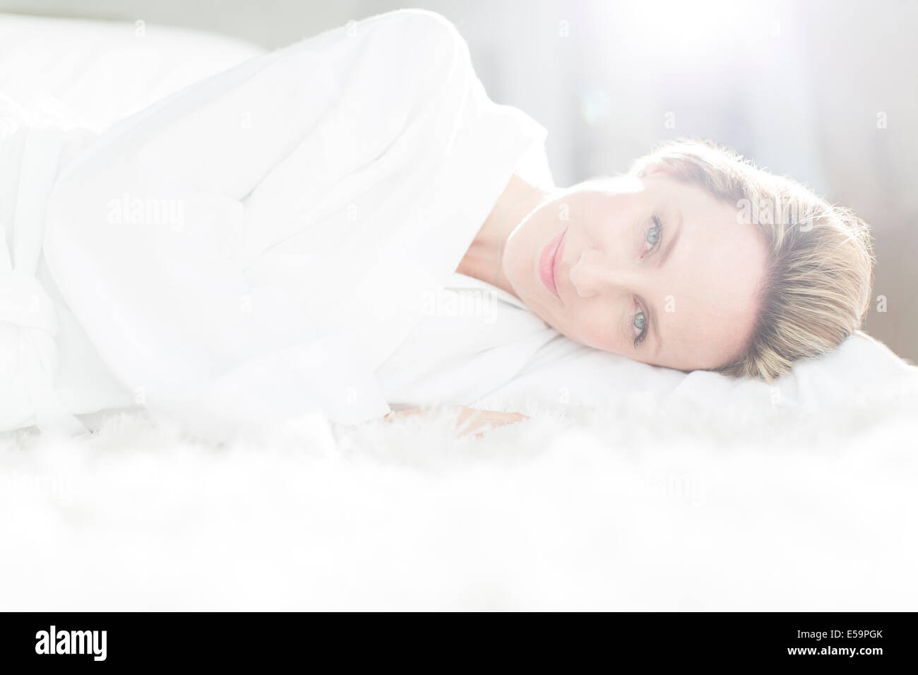 Frau im Bademantel auf Bett Stockfoto