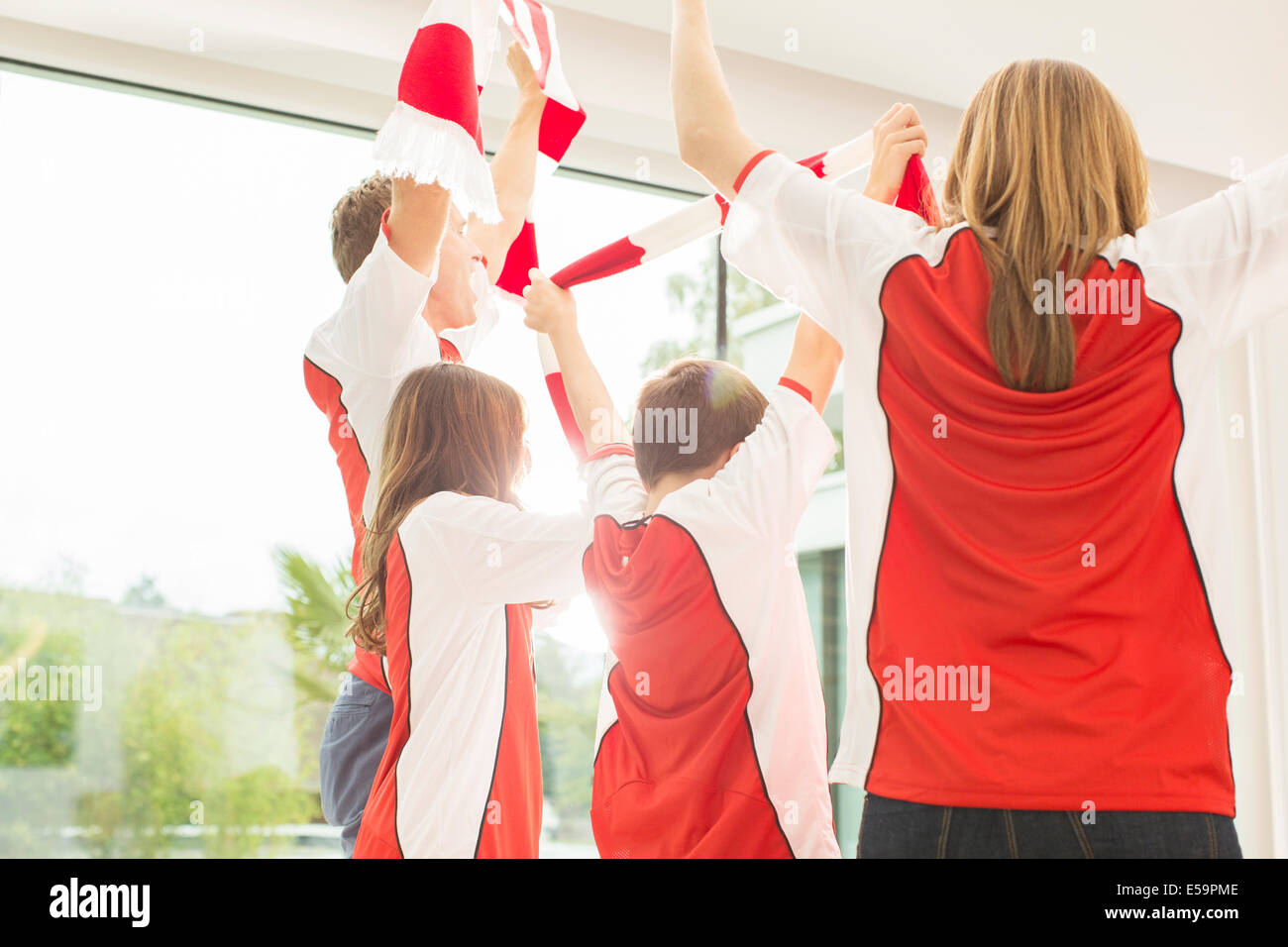 Familie in Sporttrikots zusammen jubeln Stockfoto