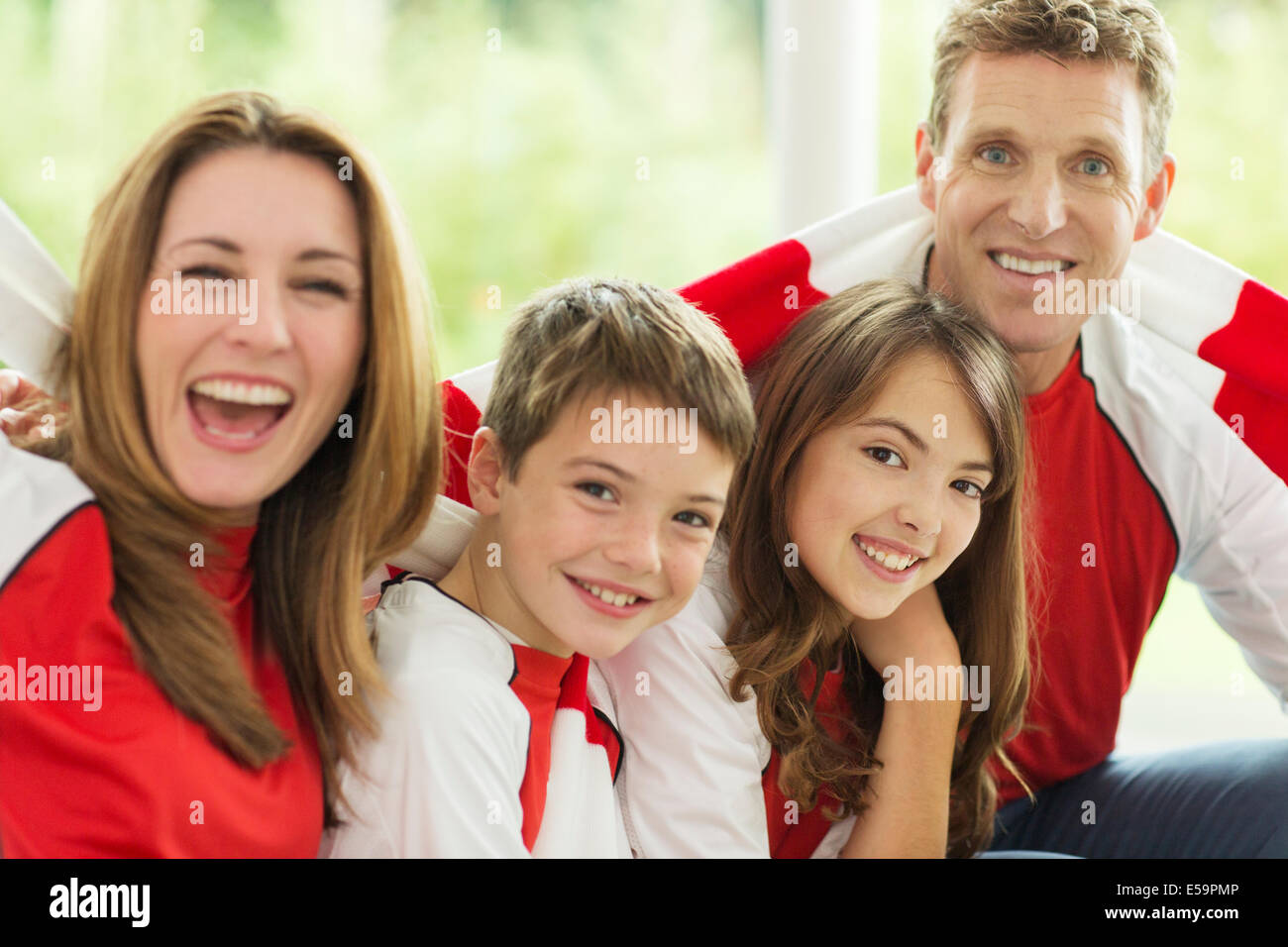 Familie in Sporttrikots Jubel im Wohnzimmer Stockfoto