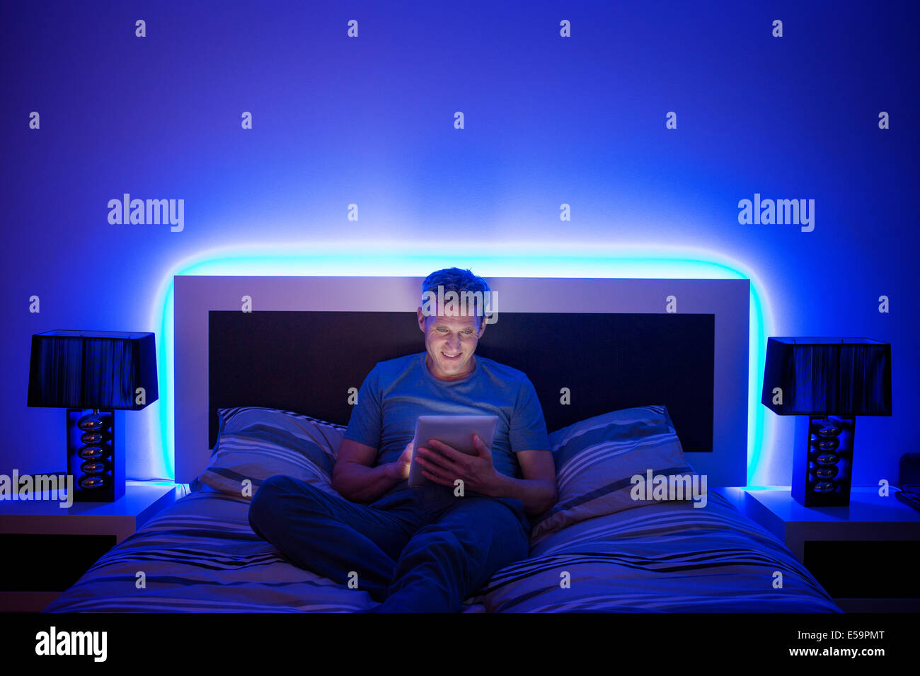 Mann mit digital-Tablette im Bett Stockfoto