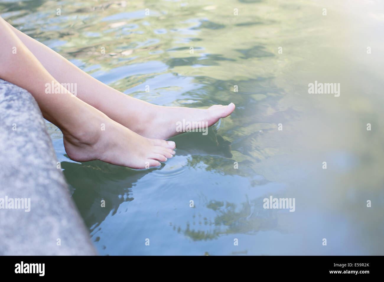 Frau, die Füße im Teich eintauchen Stockfoto