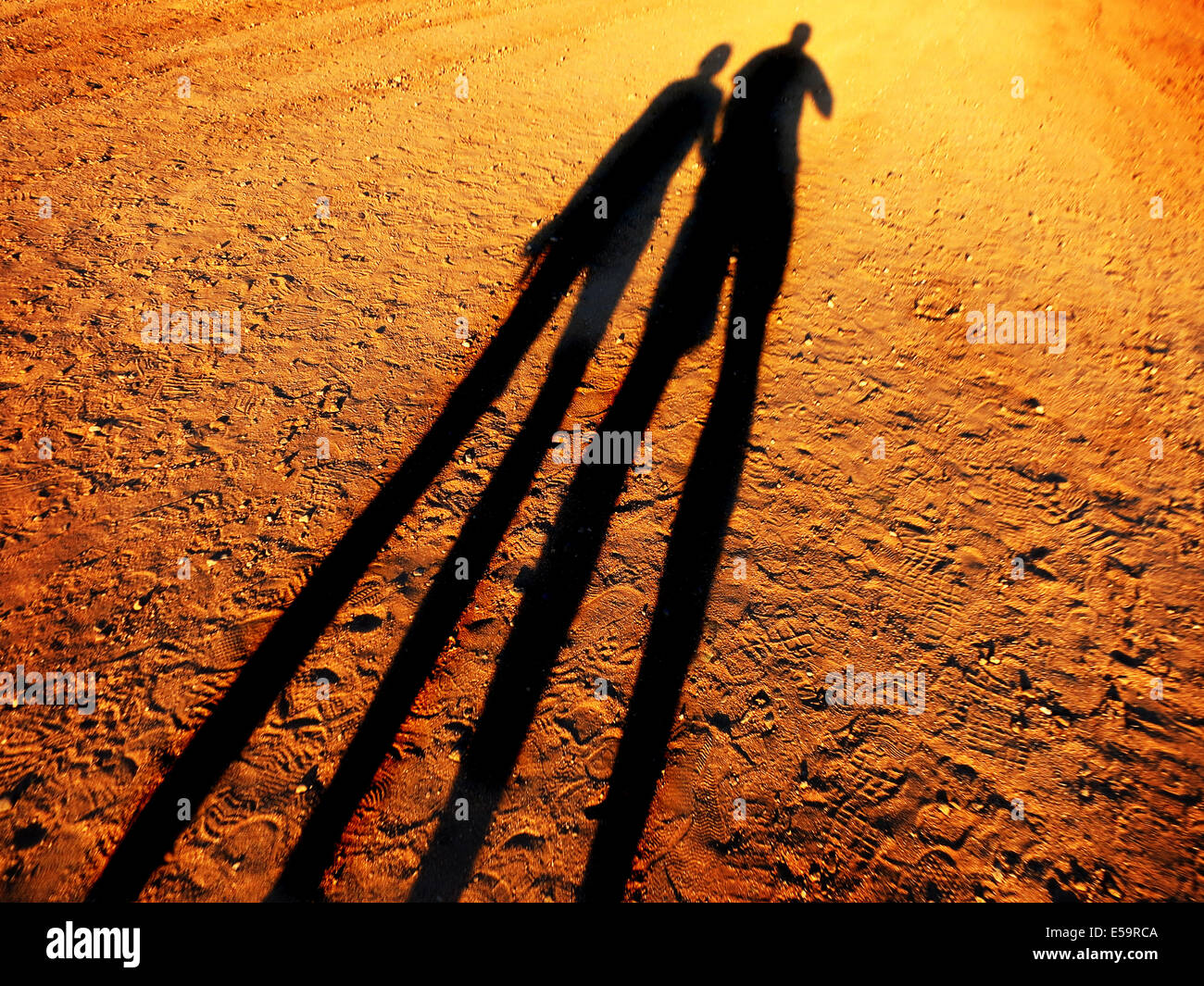 Schatten von zwei Menschen Hand in Hand zusammen eine Schotterstraße hinunter Stockfoto