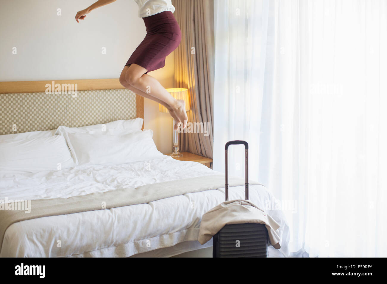 Geschäftsfrau, die springen auf Bett im Hotelzimmer Stockfoto