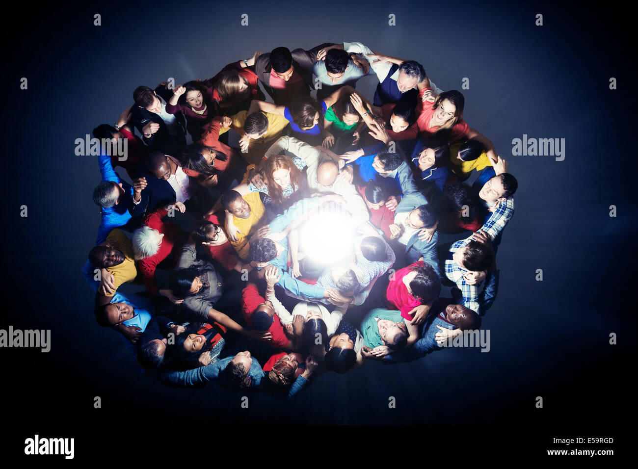 Heterogene Gruppe im Huddle um Licht Stockfoto