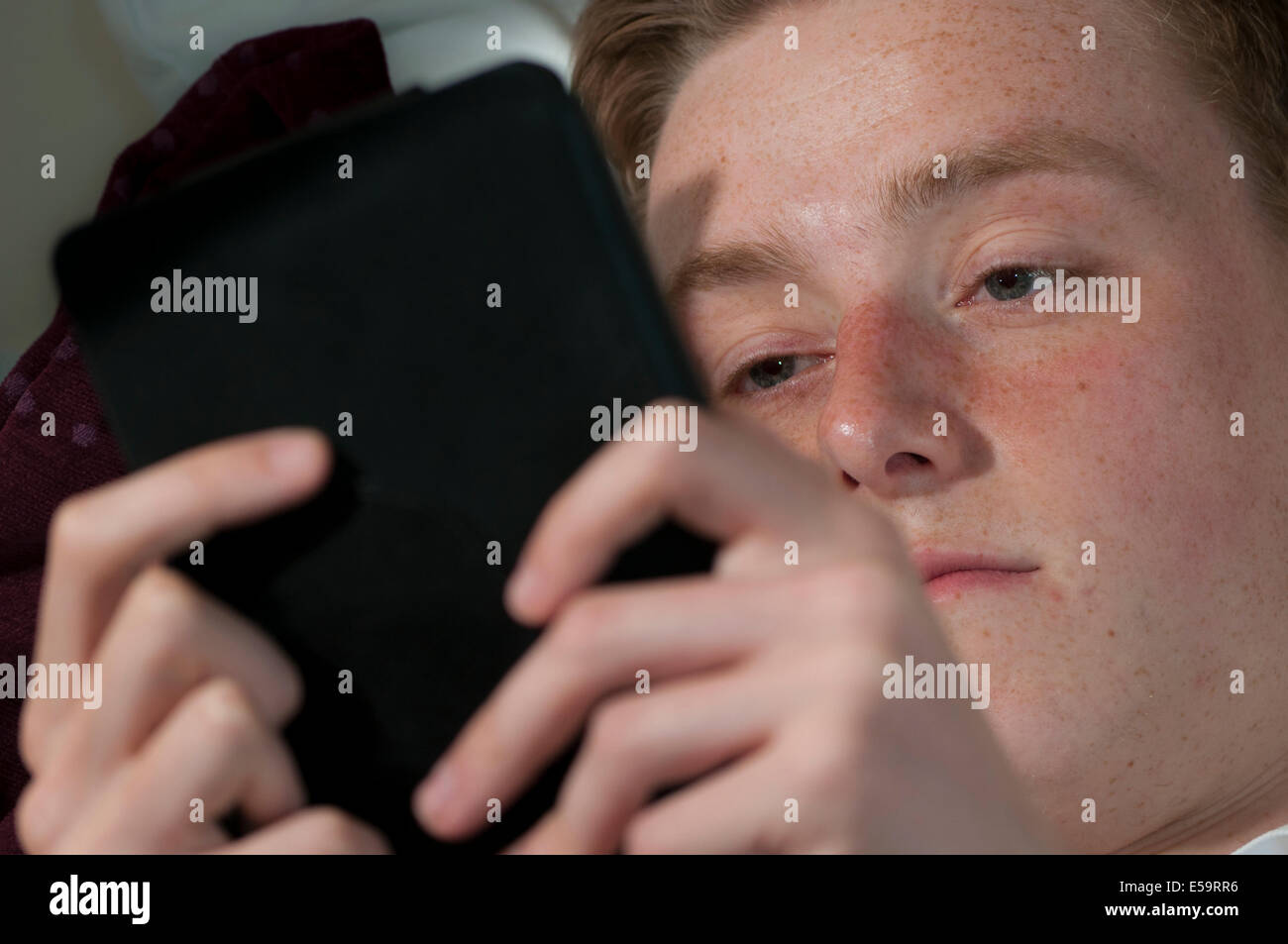 Männliche Jugend junge Mann liest e-Reader Kindle in Buch vertieft Stockfoto