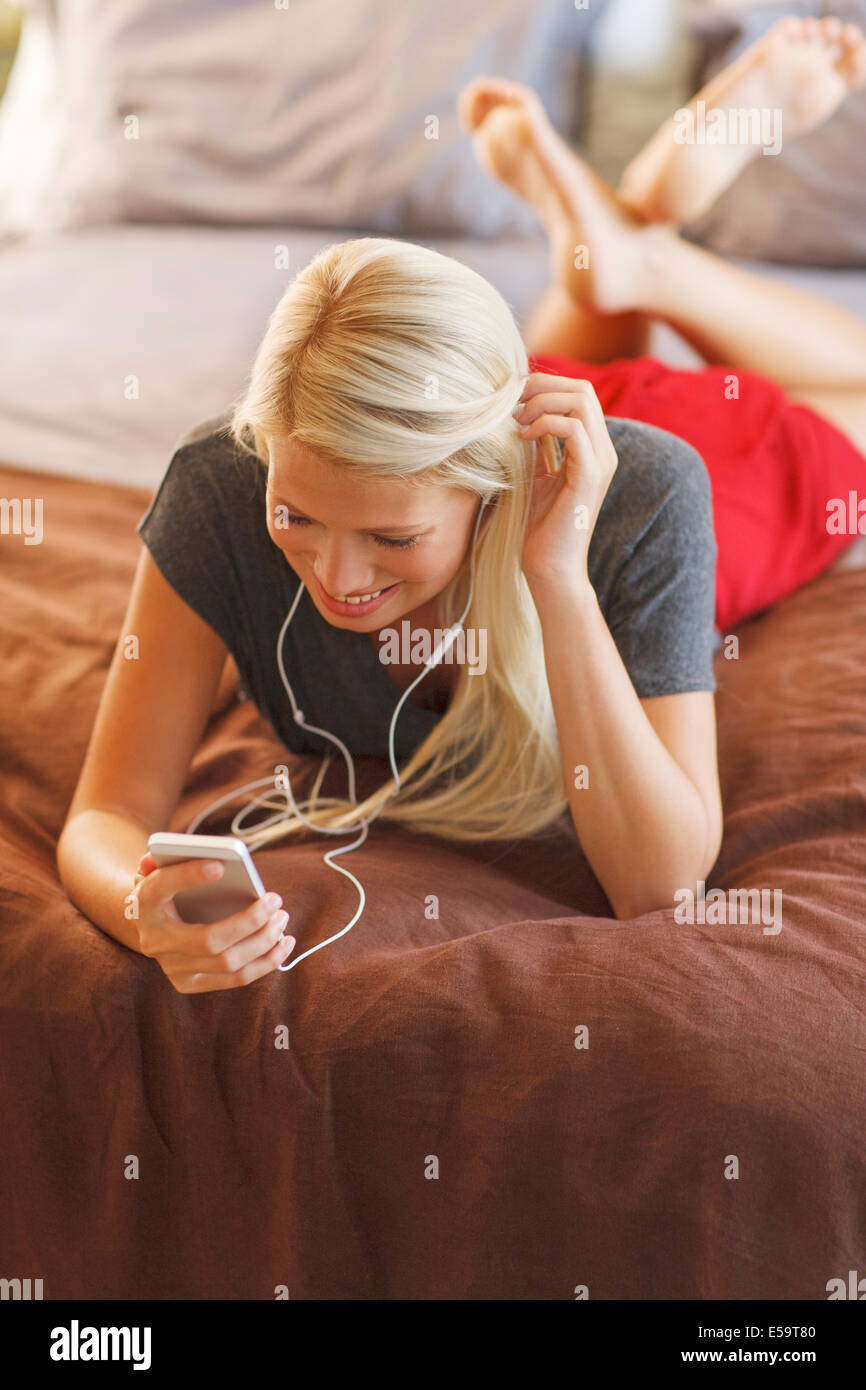 Frau, anhören von MP3-Player auf Bett Stockfoto