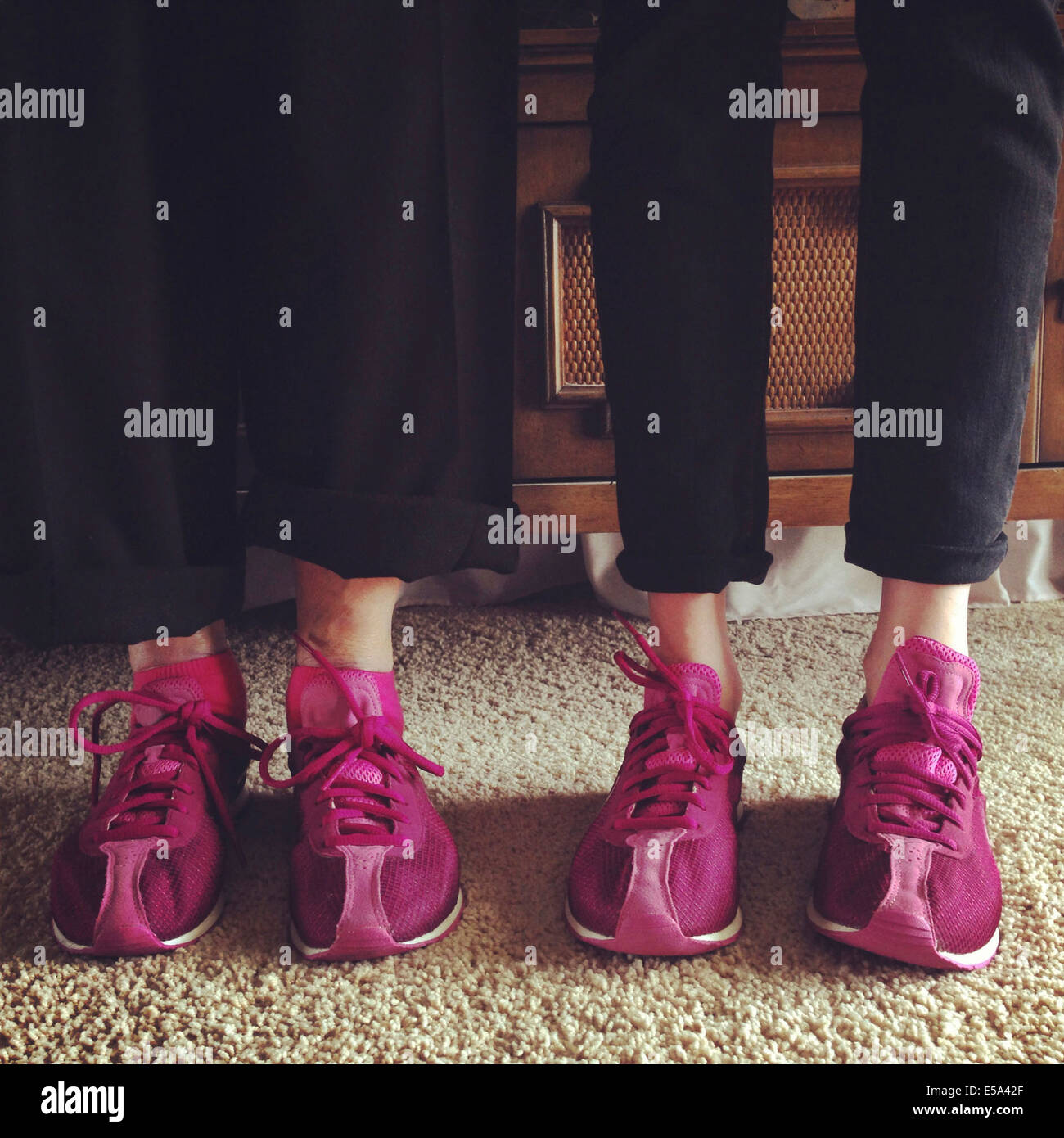 Ältere Frau und Enkelin mit passenden Schuhen im Wohnzimmer - Smartphone-aufgenommenes Stockfoto