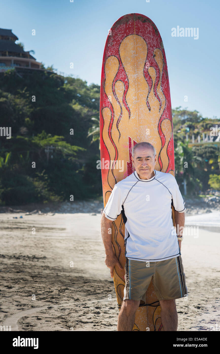 Älteren Hispanic Mann mit Surfbrett am Strand Stockfoto