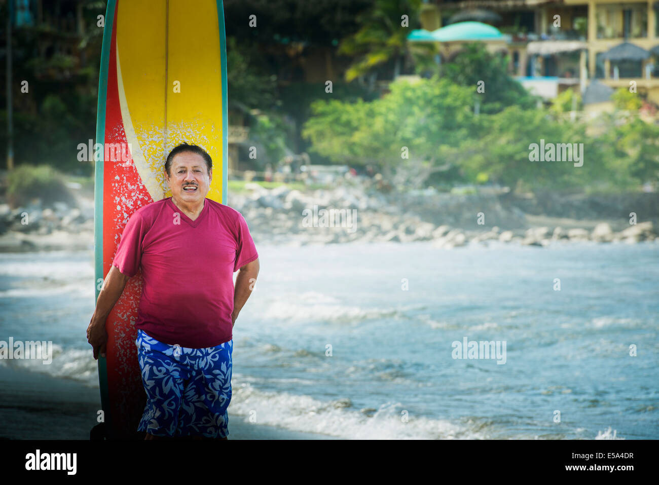 Älteren Hispanic Mann mit Surfbrett am Strand Stockfoto
