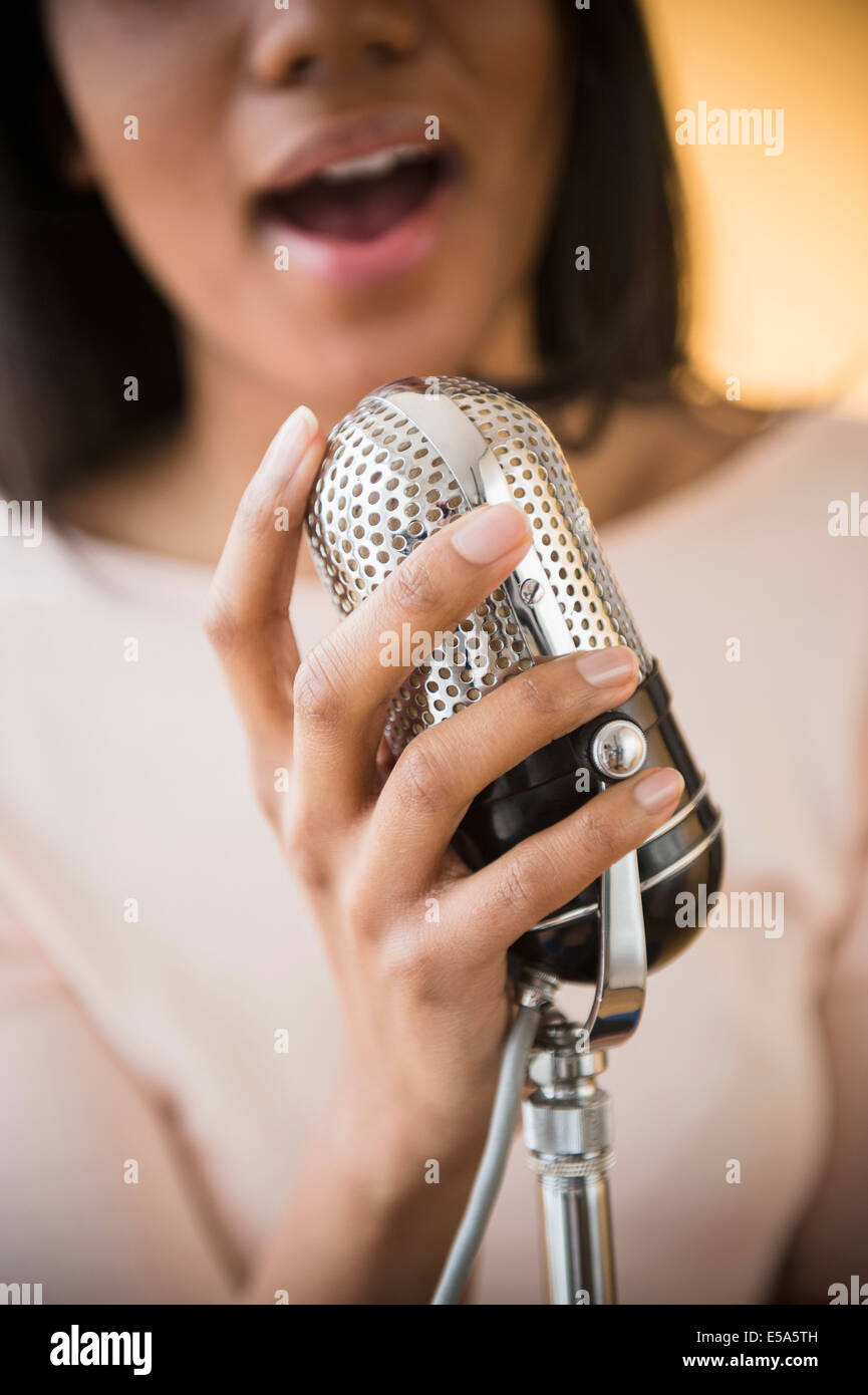 Gemischte Rassen Frau singt in Vintage Mikrofon Stockfoto