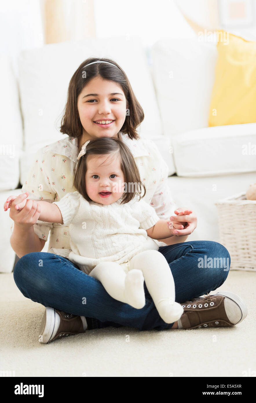 Hispanischen Mädchen halten Kleinkind Schwester im Wohnzimmer Stockfoto
