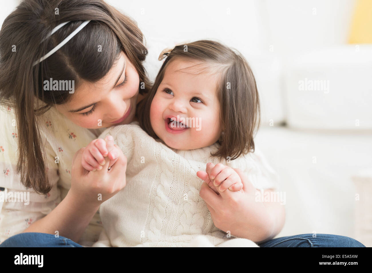 Hispanischen Mädchen halten Kleinkind Schwester im Wohnzimmer Stockfoto