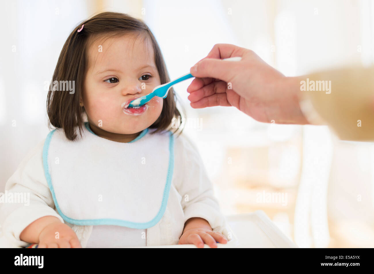 Hispanische Mutter füttert Kleinkind im Hochstuhl Stockfoto