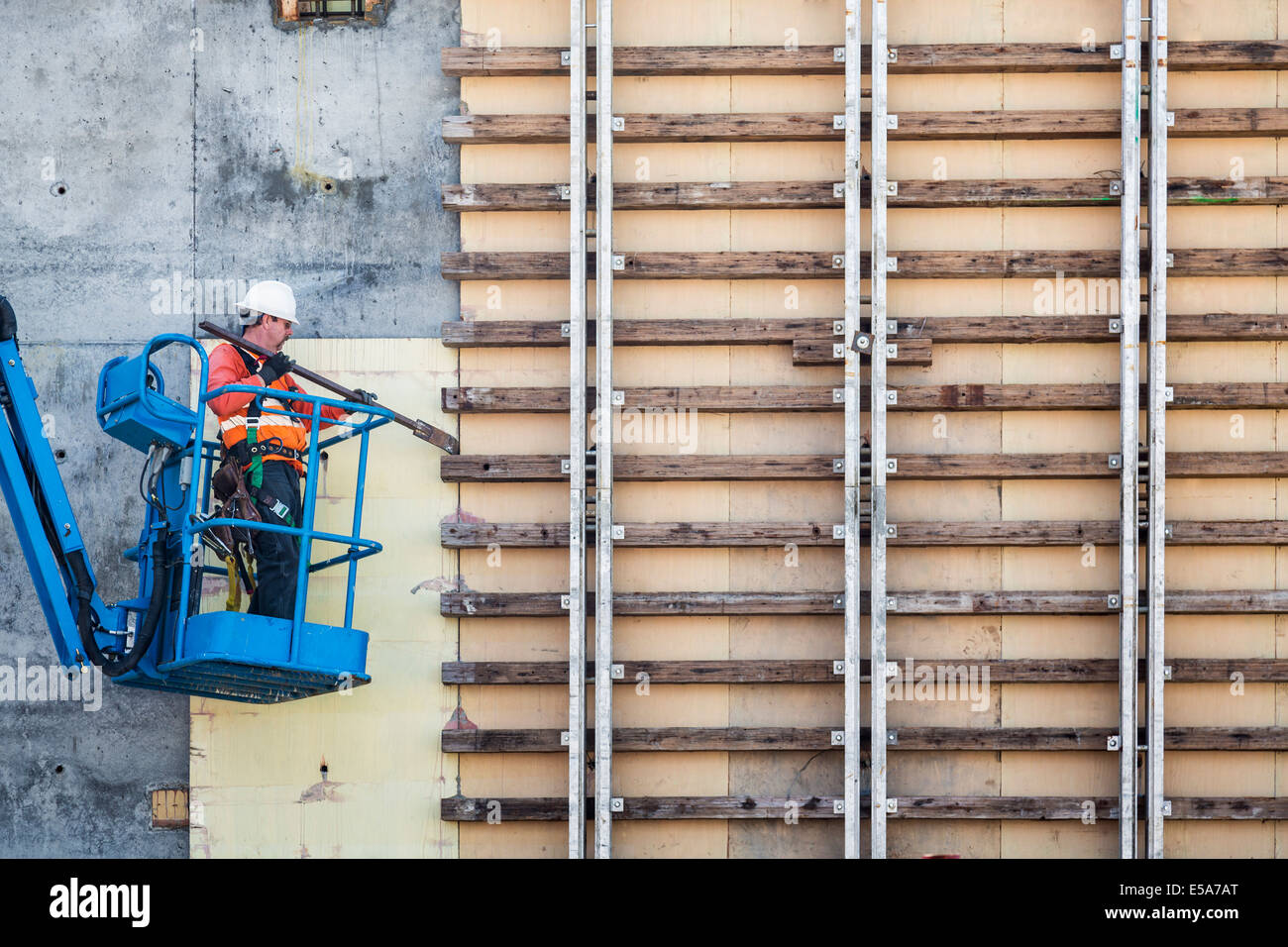 Kaukasische Arbeiter auf Arbeitsbühne arbeitet auf Baustelle Stockfoto