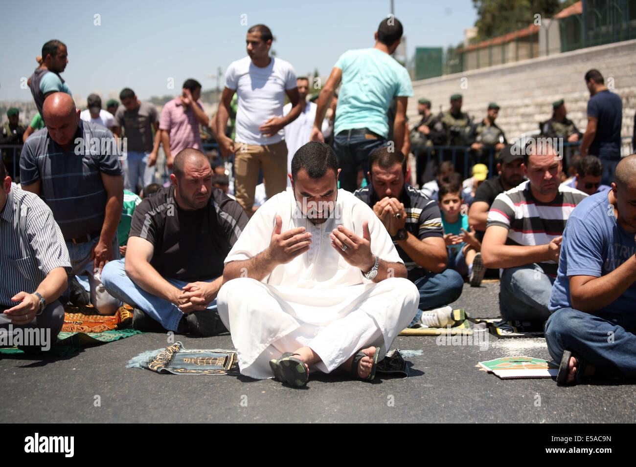 Jerusalem, Jerusalem, Palästina. 25. Juli 2014. Israelische bewaffnete Polizisten Wache hinter palästinensischen Moslems Durchführung der traditionellen Freitagsgebet in der Nähe der Altstadt in Ost-Jerusalem auf. Israelische Sicherheitskräfte sind in erhöhter Alarmbereitschaft, nachdem ein palästinensischer Mann tot während einer großen Protestaktion im Westjordanland gegen Israels Militäroffensive im Gaza-Streifen gedreht wurde. Bildnachweis: ZUMA Press, Inc./Alamy Live-Nachrichten Stockfoto